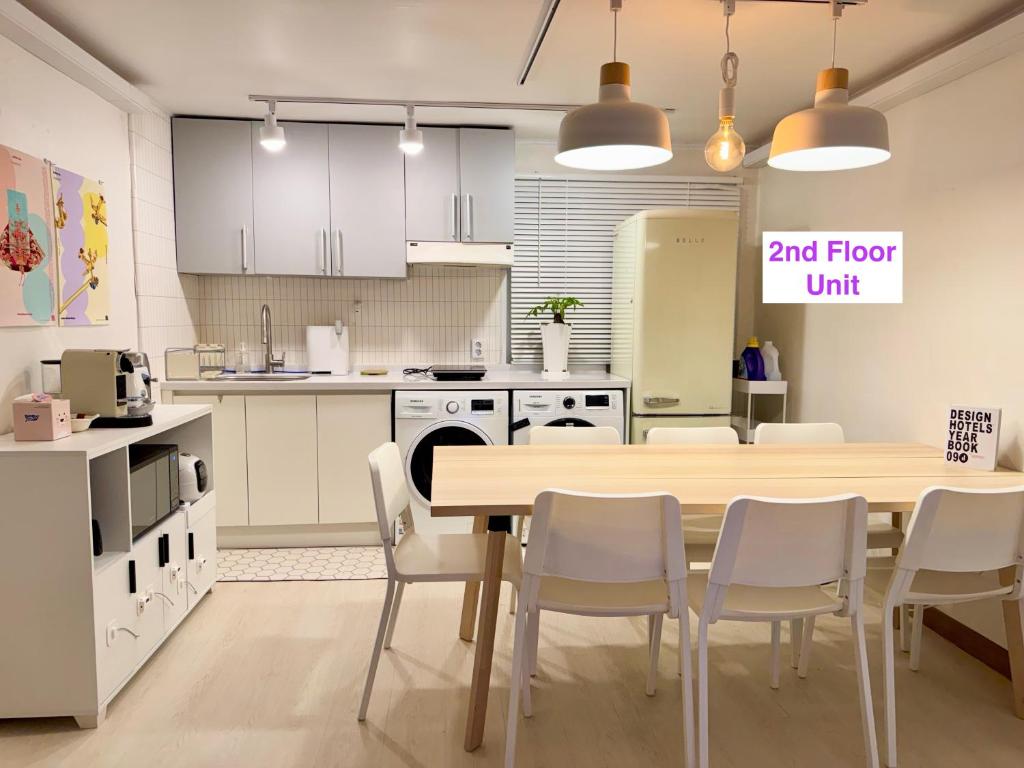 a kitchen with a wooden table and white chairs at Pachira House in Seoul