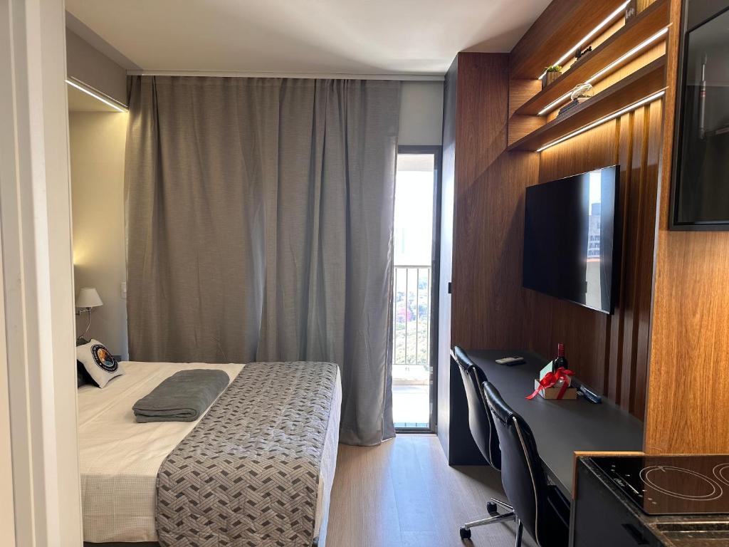 Un dormitorio con una cama y un escritorio con televisión. en Studio NOVO 100m Av Paulista, en São Paulo