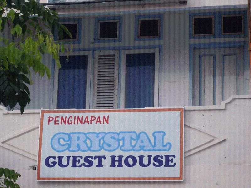 um sinal para uma casa de hóspedes em frente a um edifício em Crystall Guesthouse em Banda Aceh