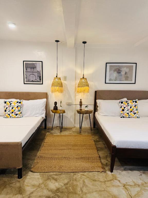 two beds in a room with two tables at E-Place Resort in Magallanes