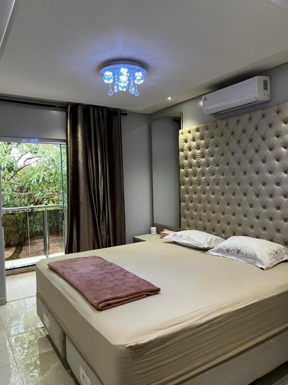 a bedroom with a large bed and a large window at Apartamento aconchegante com estacionamento privado in Salto del Guairá