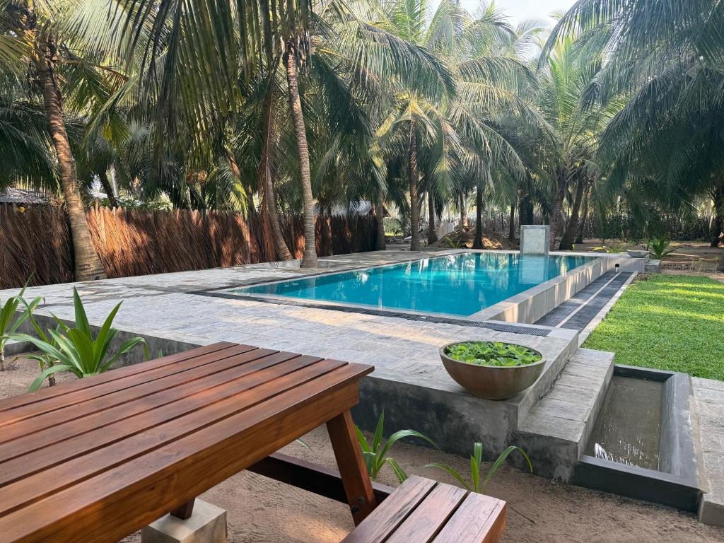 a swimming pool with a bench and a table at Agro Village Resort , Kalpitiya in Kalpitiya