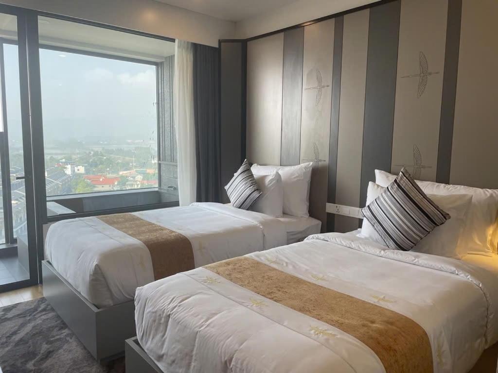 zwei Betten in einem Hotelzimmer mit großem Fenster in der Unterkunft Wyndham Lynn Times Thanh Thủy in La Phu