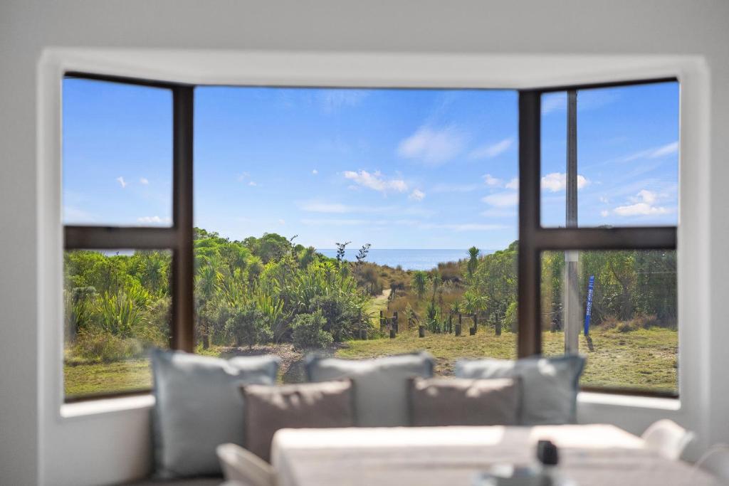 Habitación con vistas al campo a través de una ventana. en Sandbanks - Papamoa Beachfront Holiday Home, en Papamoa