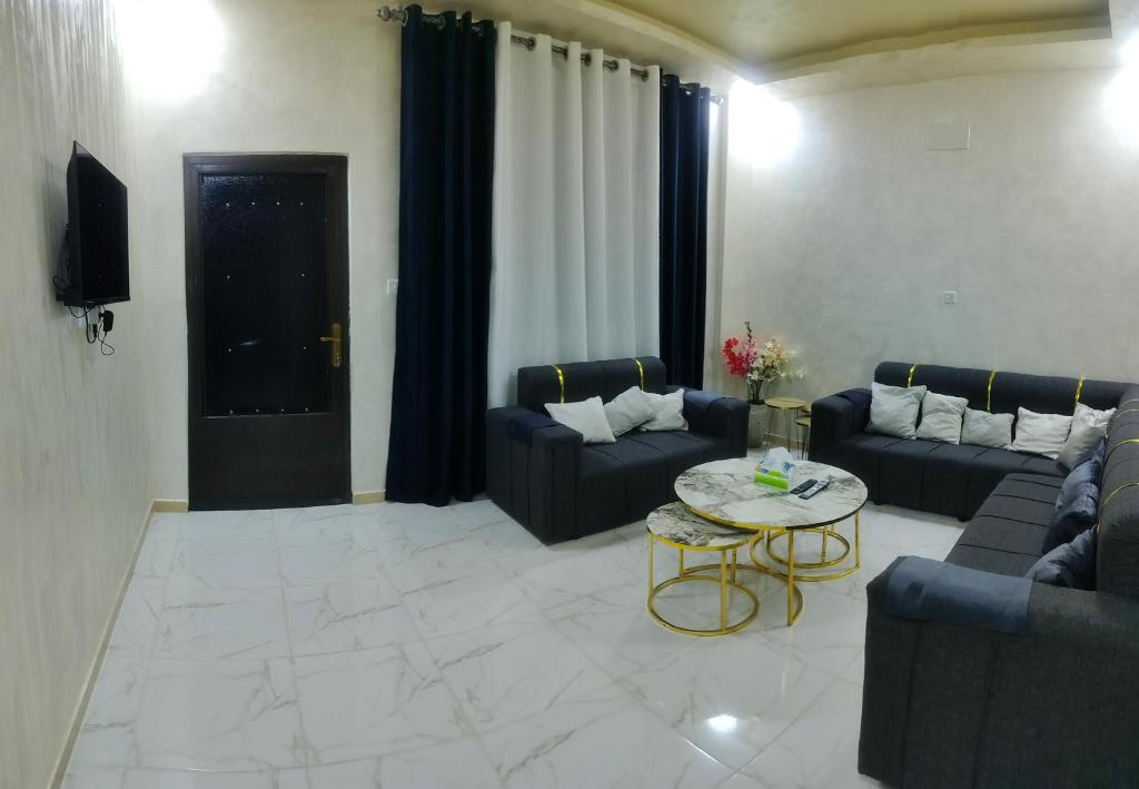 a living room with couches and a table and a tv at Furnished apartments for rent 1 in Aqaba