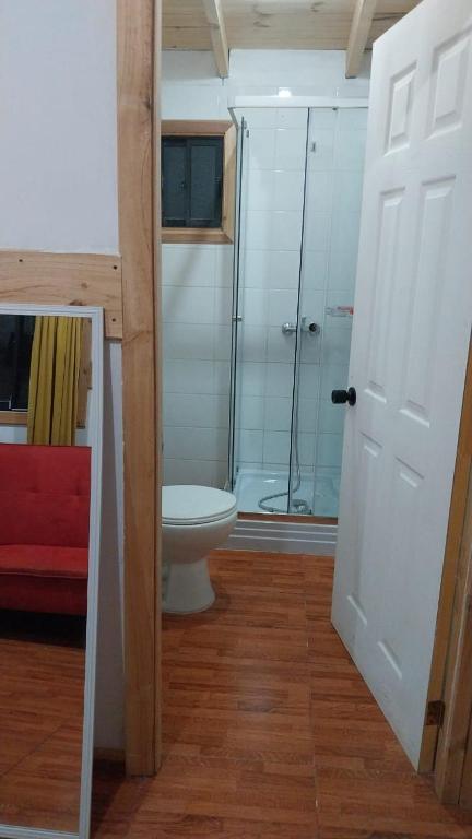a bathroom with a toilet and a glass shower at Complejo Infinitus in Lanco