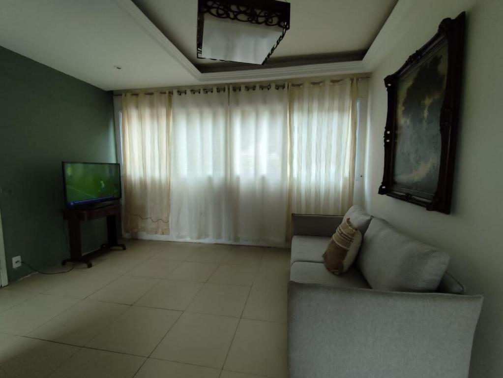 a living room with a couch and a television at Rota das Praias in Vila Velha
