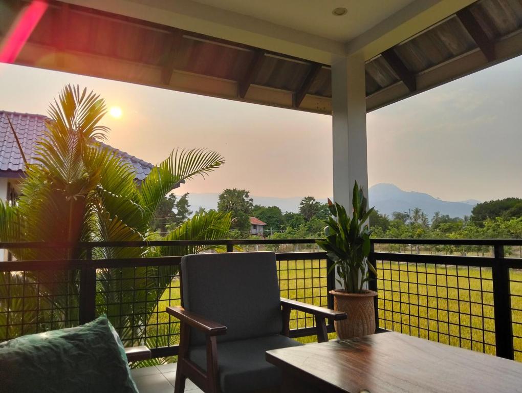 a balcony with a chair and a table and a view at Baksaei Retreat Ricefield Villas in Kampot