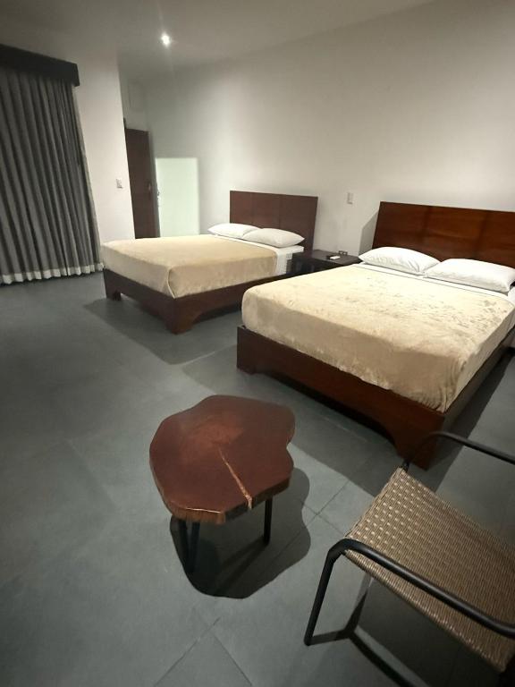 Habitación con 2 camas y taburete. en Scala Inn, en Muelle