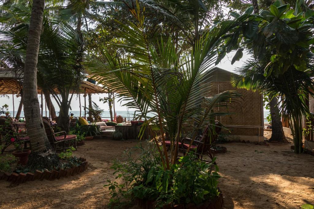 a patio with palm trees and tables and chairs at Jardim a Mar in Agonda