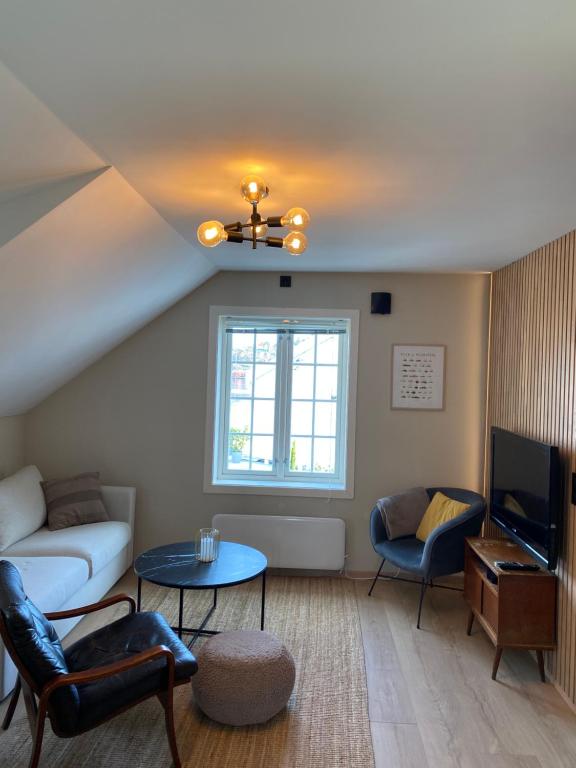 a living room with a couch and a tv at Nice apartment close to the sea with parking and garden in Arendal