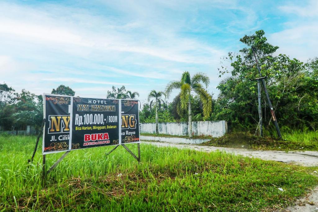 ein Schild im Gras neben einer Straße in der Unterkunft Hotel O Nyi Rindang Near Puskesmas Jekan Raya in Palangkaraya