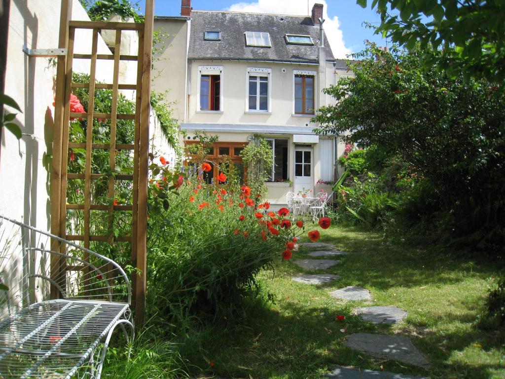 un jardín frente a una casa con flores rojas en Le Petit Quernon en Angers