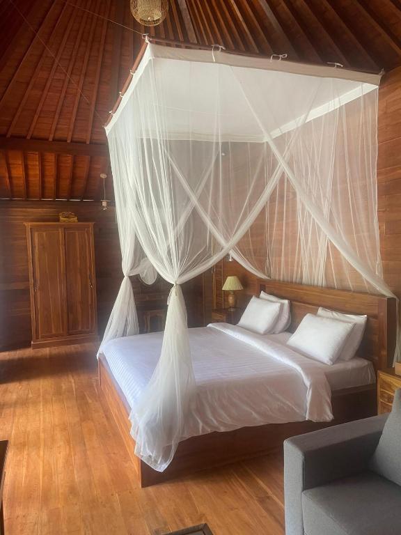 a bedroom with a canopy bed with white sheets and pillows at Dewaka Villa in Ubud