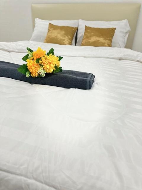 a white bed with a bouquet of flowers on it at Ct House in Chiang Mai