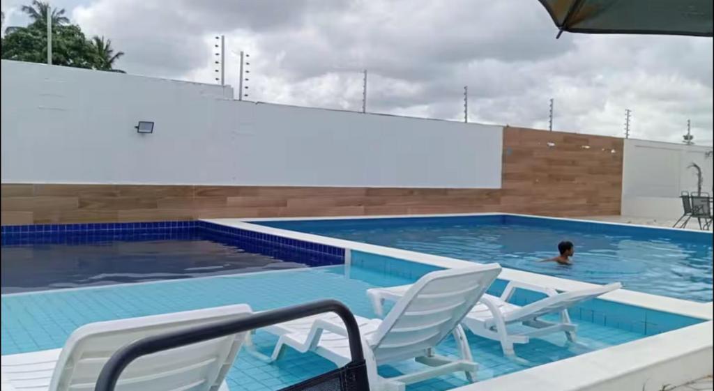 a swimming pool with chairs and a person in the water at Casa em Parnaíba 6km praia in Parnaíba