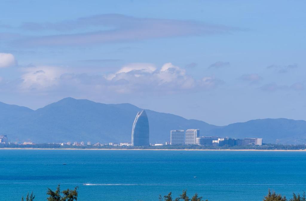 a view of a city and the ocean with mountains in the background at Fuwan Haitao Meishu -Lingshui Haitang Bay Branch in Sanya