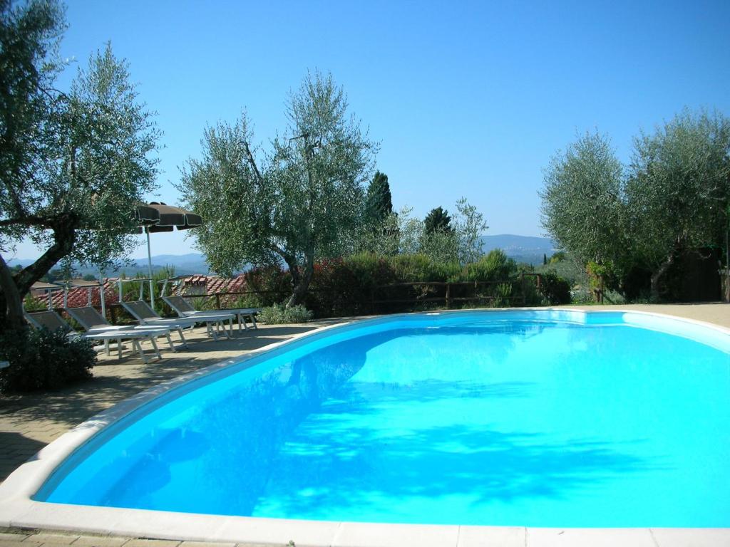 ポッジボンシにあるEnjoy the Tuscan landscape in a farmhouse with pool and wifiの青い大型スイミングプール(椅子、木付)