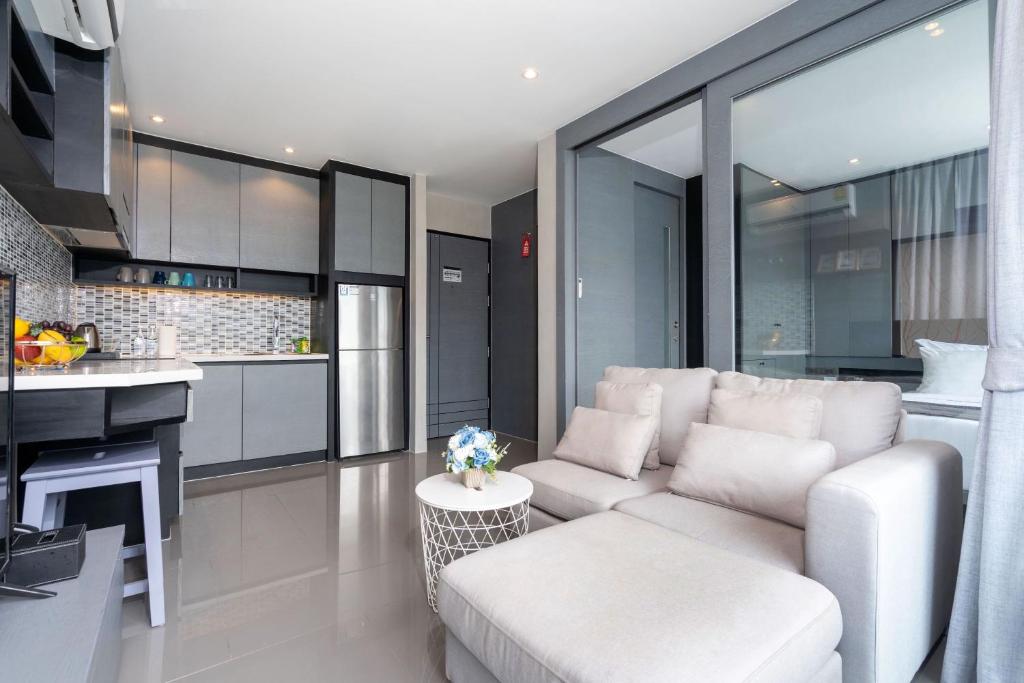 a living room with a white couch and a kitchen at Tropics Kamala Residence CTG L709, Several Pools, near Phuket Fantasea & Beach in Kamala Beach