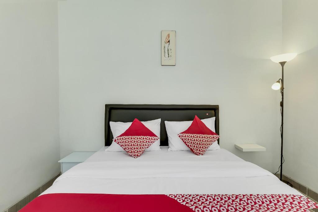 a bed with red and white pillows on it at Capital O 90983 Harmony Easy Stay in Yogyakarta