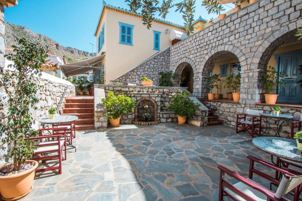 un patio al aire libre con mesas, sillas y chimenea en Alkionides Hydra, en Hydra