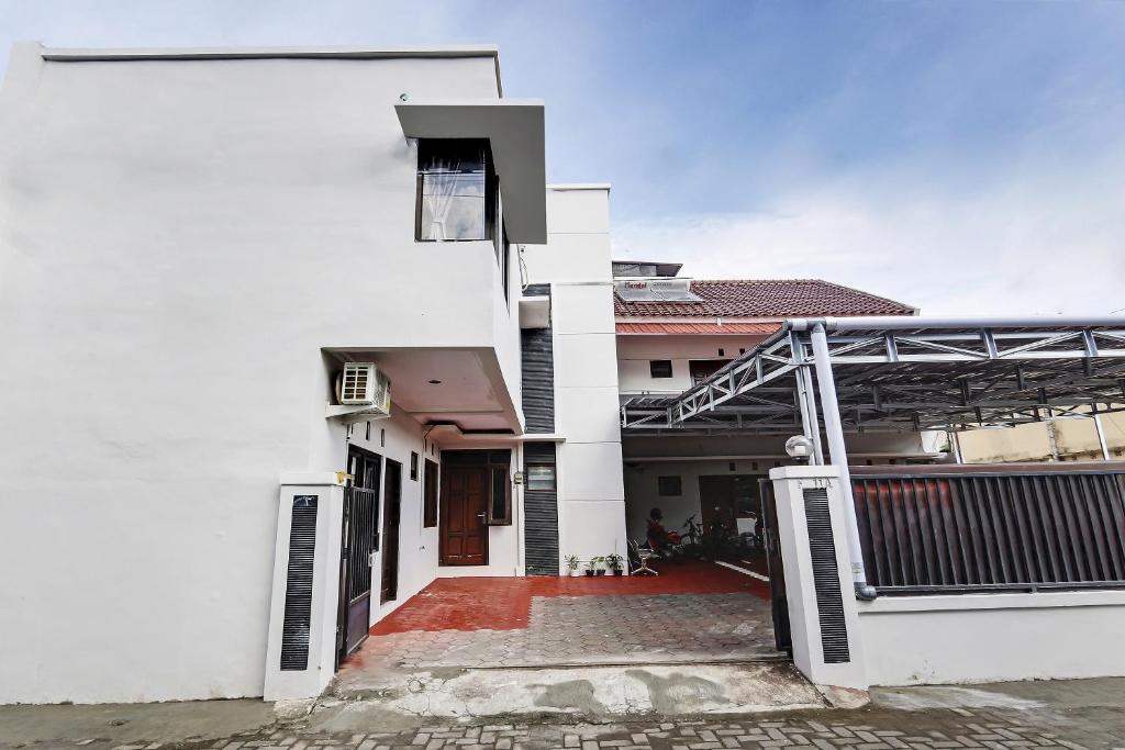 a white house with a gate and a red driveway at Hotel O Nathania Exclusive in Sleman