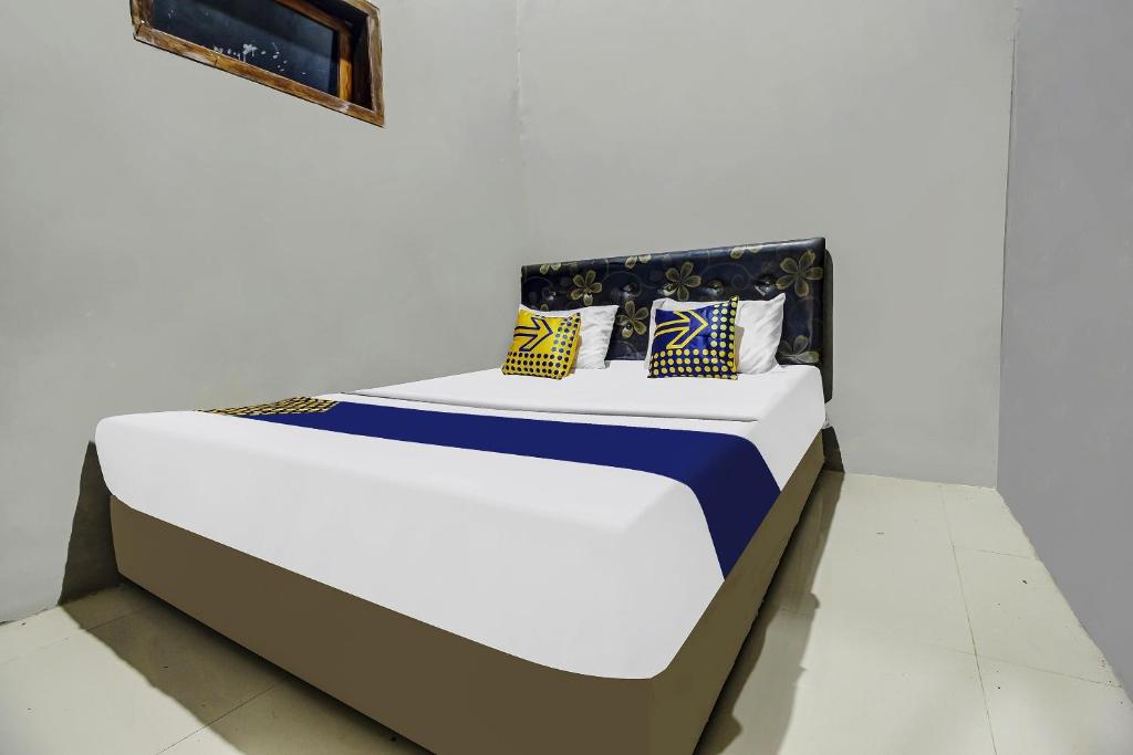 a bed in a white room with pillows on it at Hotel O Desa Wisata Kawasen in Padaherang