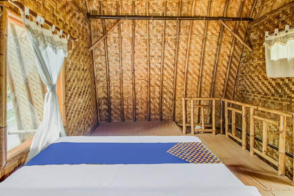 a bedroom with a bed in a bamboo house at Hotel O Desa Wisata Bangunharja in Banjar