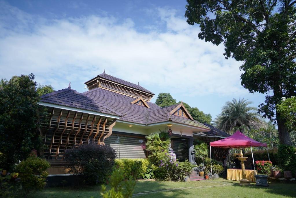 una casa con techo de gambrel en un patio en Kudajadri Heritage Pool Homestay Kothamangalam, en Kotamangalam