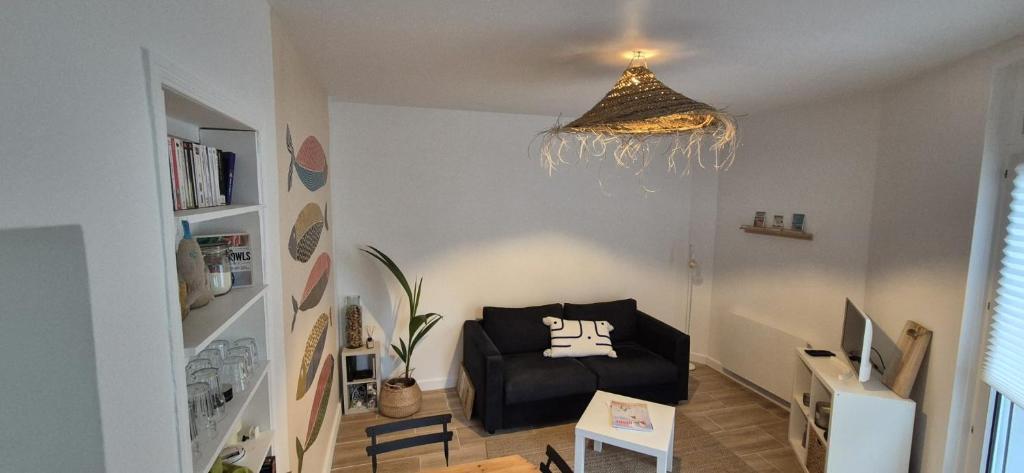 un salon avec une chaise noire et un lustre dans l'établissement La Baule, Plein Centre/Terrasse, à La Baule