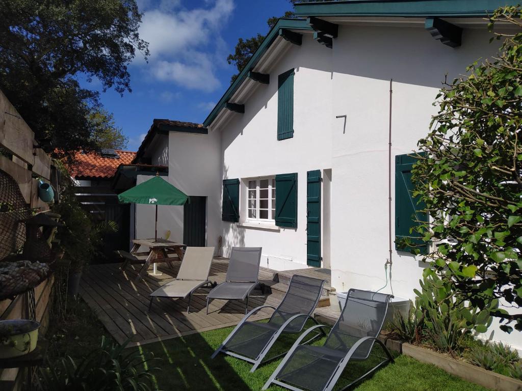 un groupe de chaises et un parasol sur une terrasse dans l'établissement Charming villa near Hossegor golf and lake, à Capbreton