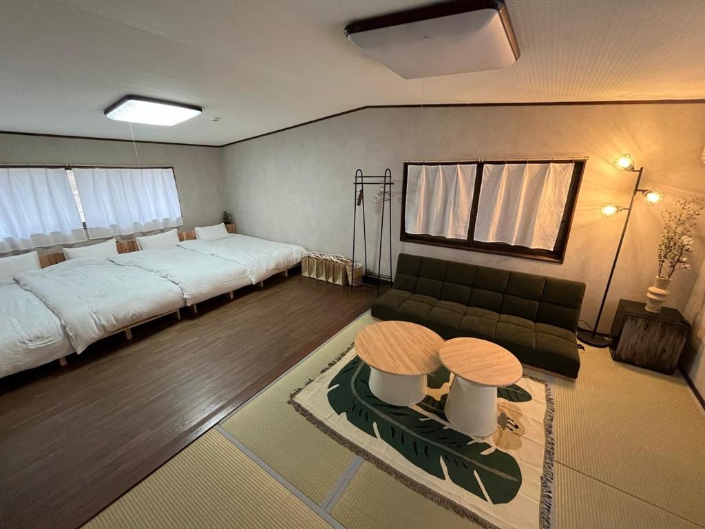 a bedroom with a bed and a couch and two tables at 泊まれるカフェやわらかそう in Koka