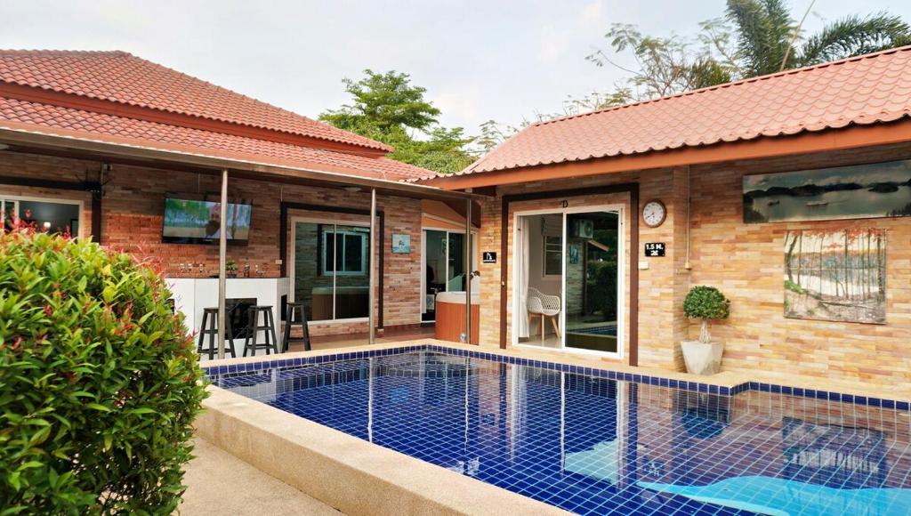 eine Villa mit einem Swimmingpool vor einem Haus in der Unterkunft Luxury 6BHK Villa with Private Pool in Pattaya by - OzyStays in Nong Prue