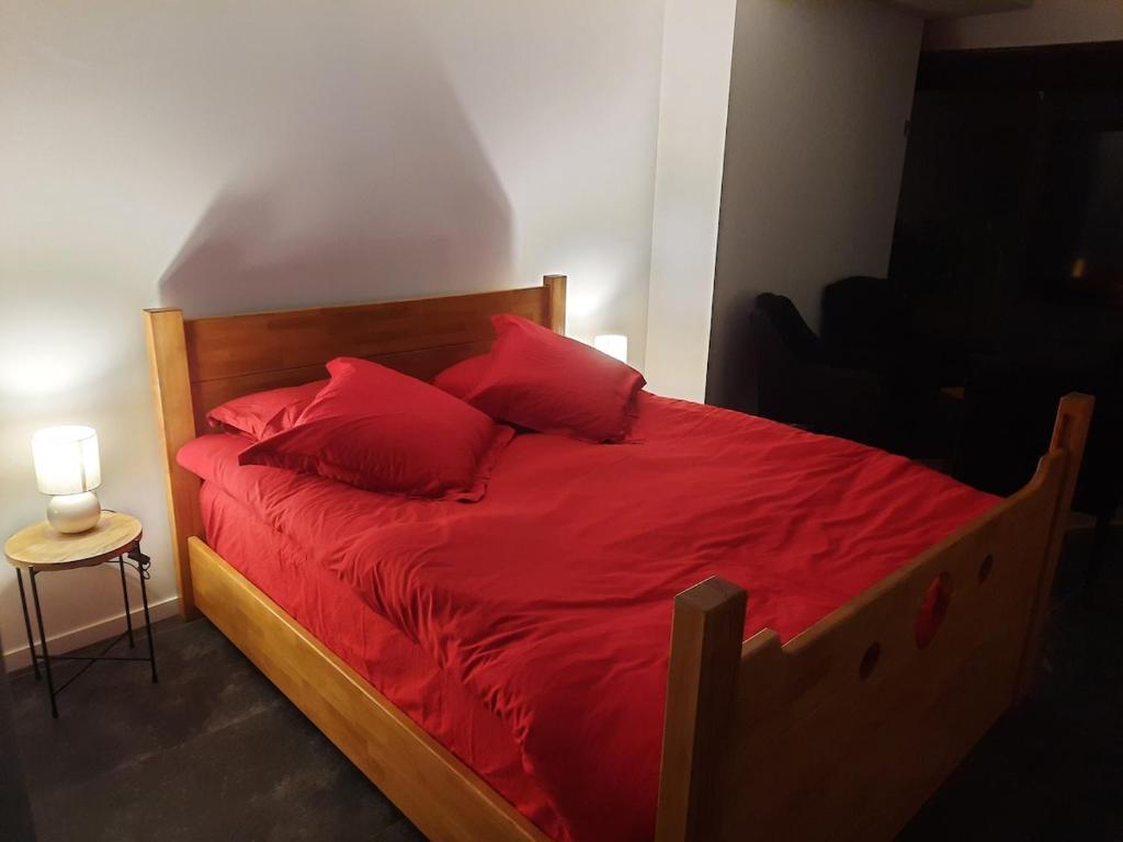 Una cama con sábanas rojas y almohadas rojas en un dormitorio. en Nuit Express à Love Suite L'Origin'El d'Ornans, en Ornans