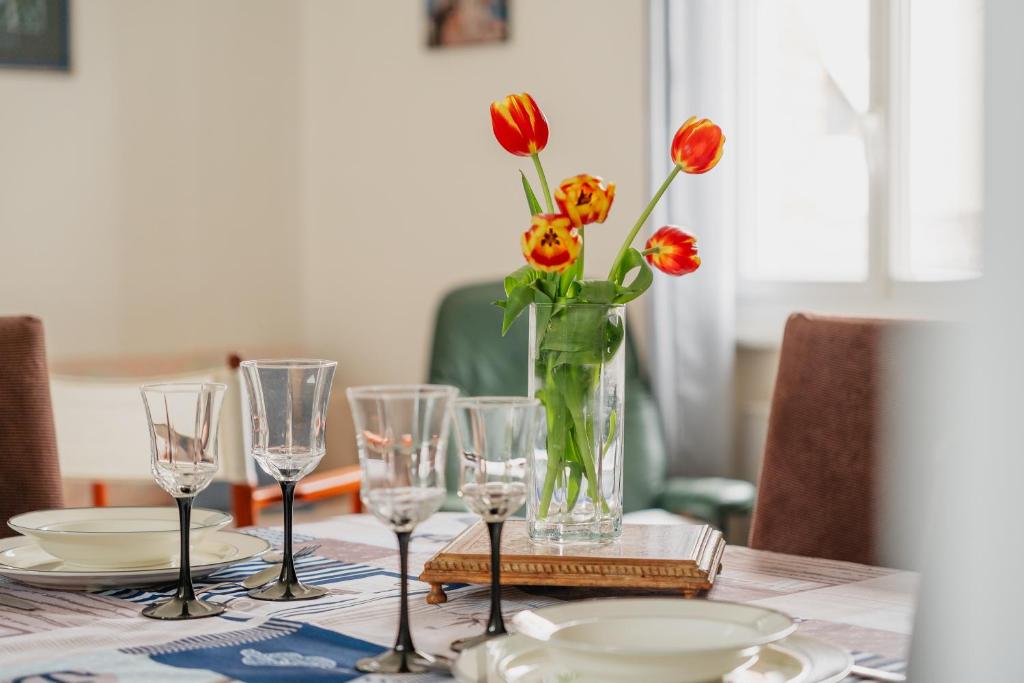une table avec un vase de fleurs et de verres dans l'établissement Appart Cancale Centre-ville - Mer, à Cancale