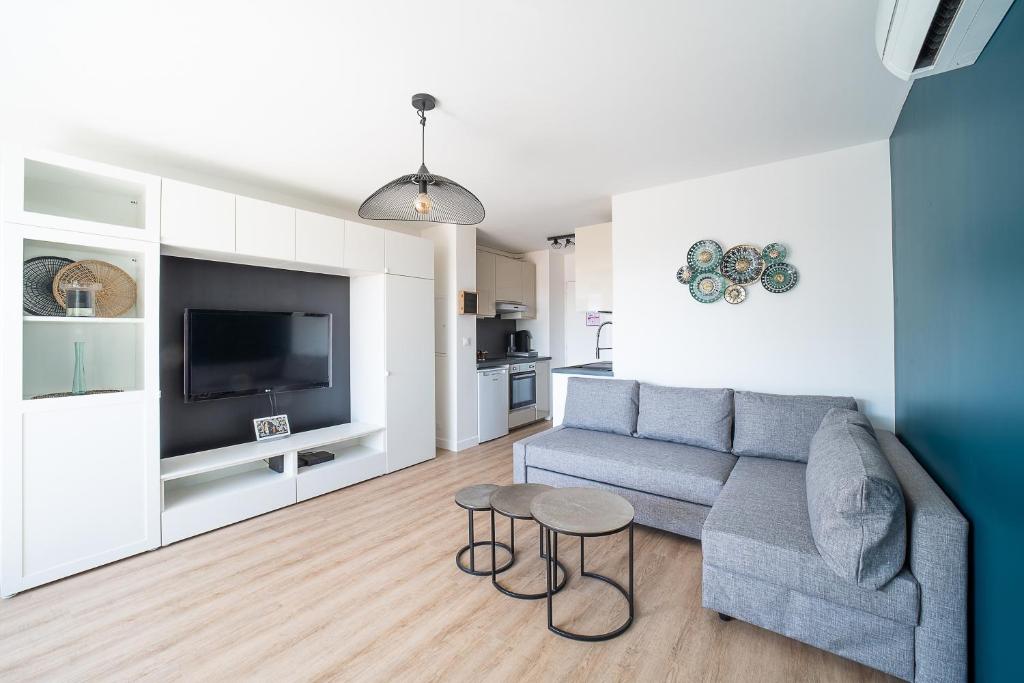 un salon avec un canapé et une télévision dans l'établissement L’Écrin du Roussillon - Studio proche mer, à Canet