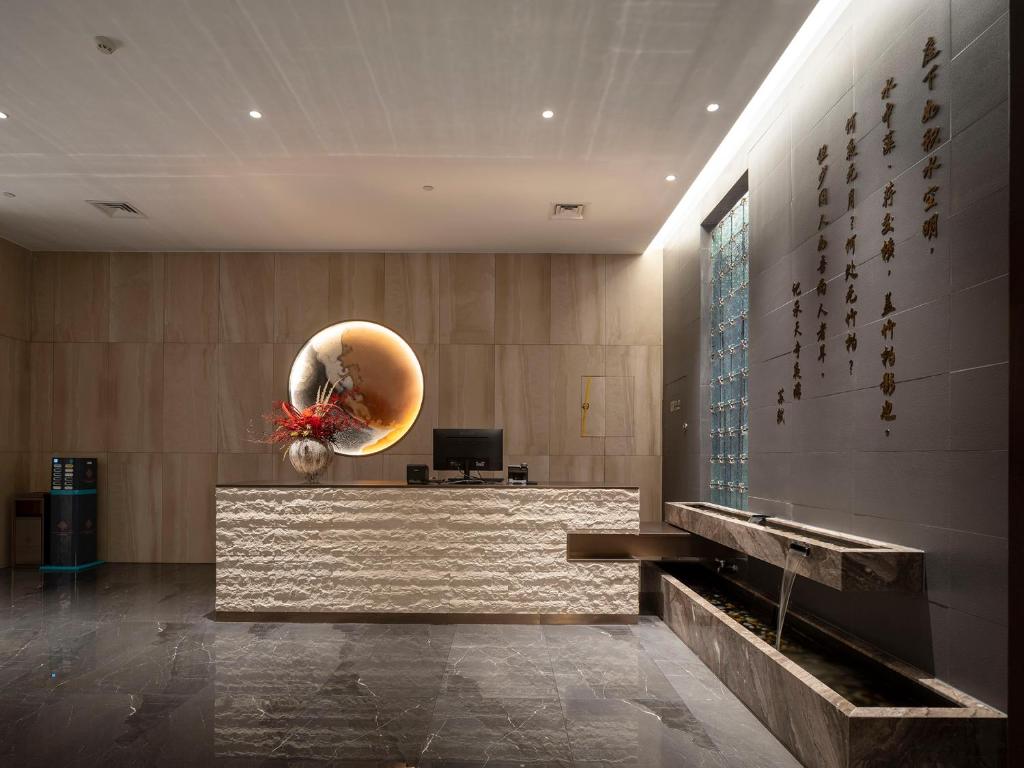 郑州Zhengzhou East Station Longzi Lake University Area Qianna Yuanxi Hotel的大楼内带前台大堂