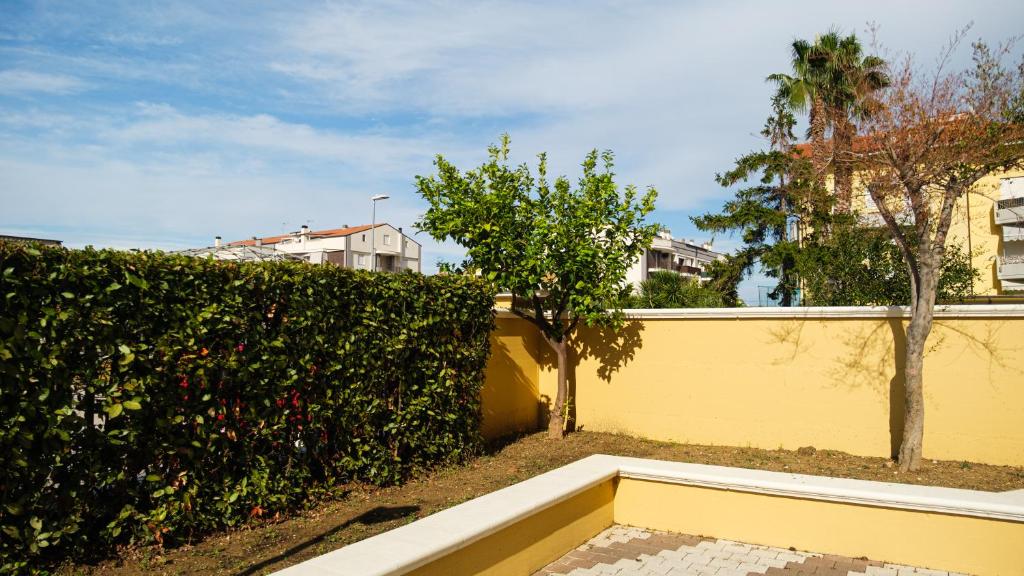 a yellow fence and a hedge with trees and houses at Smart and Sea in Tortoreto Lido
