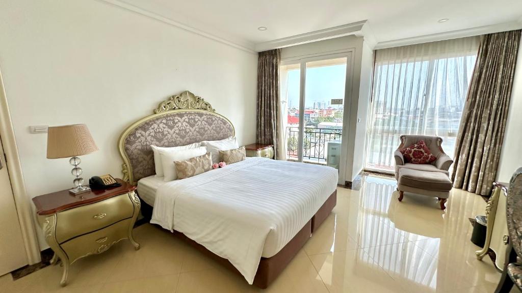 a bedroom with a bed and a chair and a window at LK CRYSTAL Ville Pattaya in Pattaya South