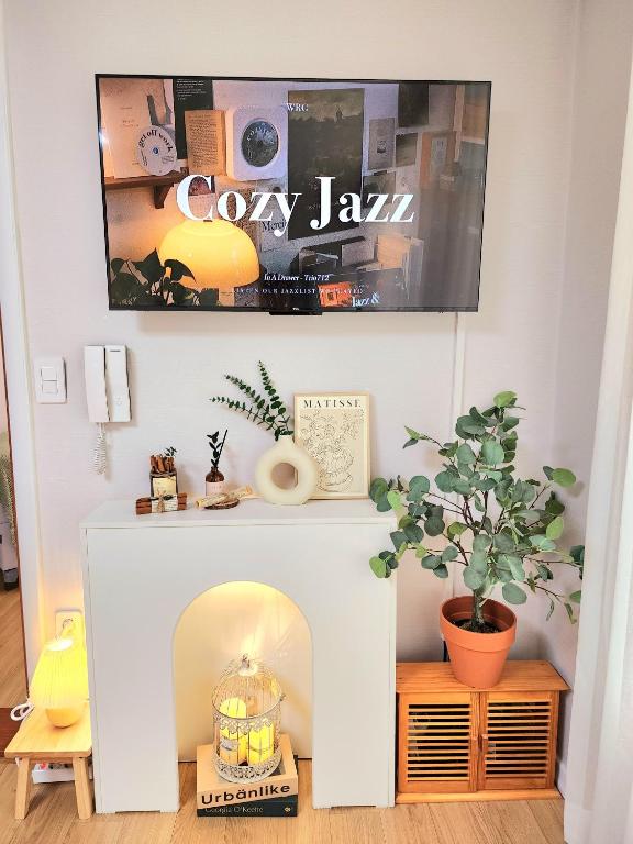 a white fireplace in a living room with a plant at 상무하우스 in Gwangju