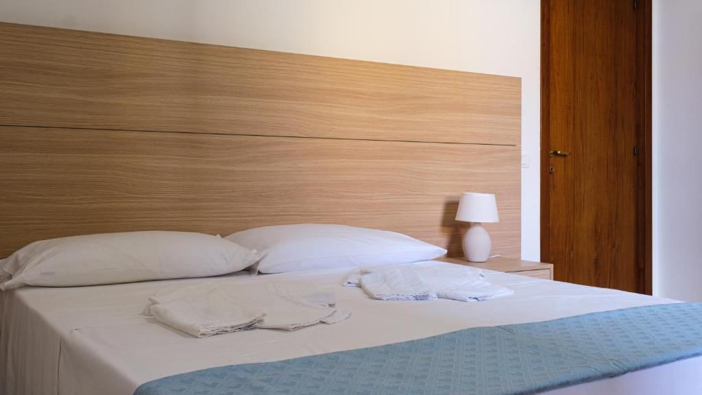 a bed with white pillows and a wooden headboard at Smart and Sea in Tortoreto Lido