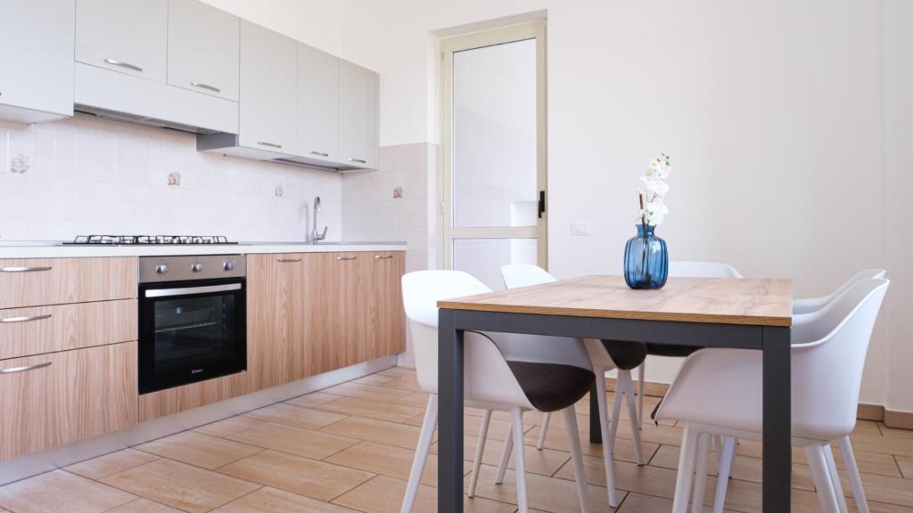 a kitchen with a wooden table and white chairs at Smart and Sea in Tortoreto Lido