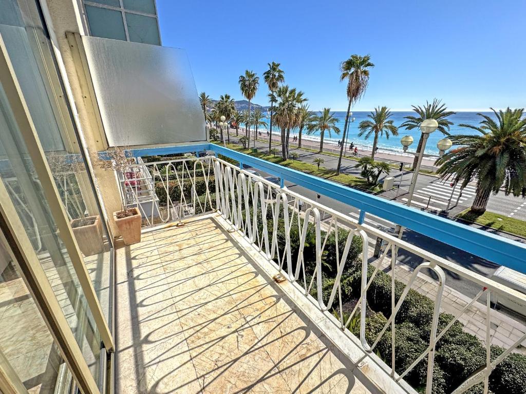 un balcon avec vue sur la plage et les palmiers dans l'établissement SUFFREN PROMENADE - PROMENADE HOLIDAY, à Nice