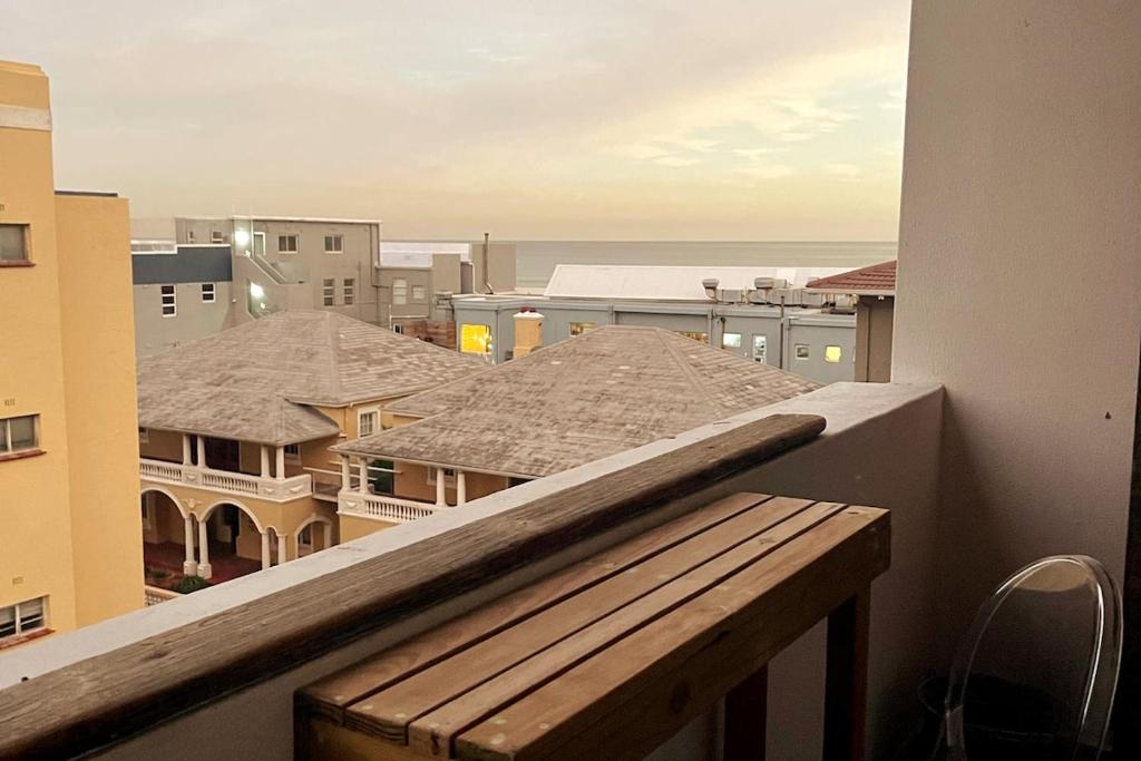 a balcony with a bench and a view of a city at Muizenberg Apartment in Muizenberg