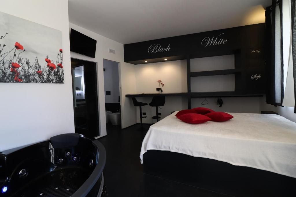 a bedroom with a bed with red pillows and a sink at Black & White Deluxe Suite Otranto Private Jacuzzi WiFi & AC Steps from Sea in Otranto