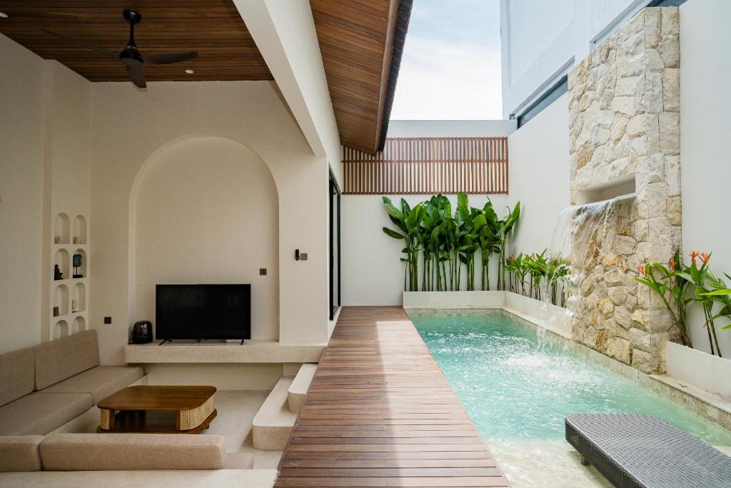 an indoor pool with a couch and a tv in a house at La Tropical Uluwatu, Bingin in Uluwatu