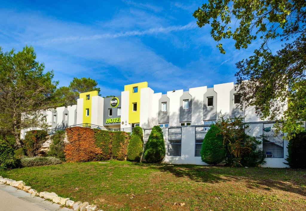 un bâtiment blanc aux accents jaunes dans l'établissement B&B HOTEL Antibes Sophia Le Relais, à Biot