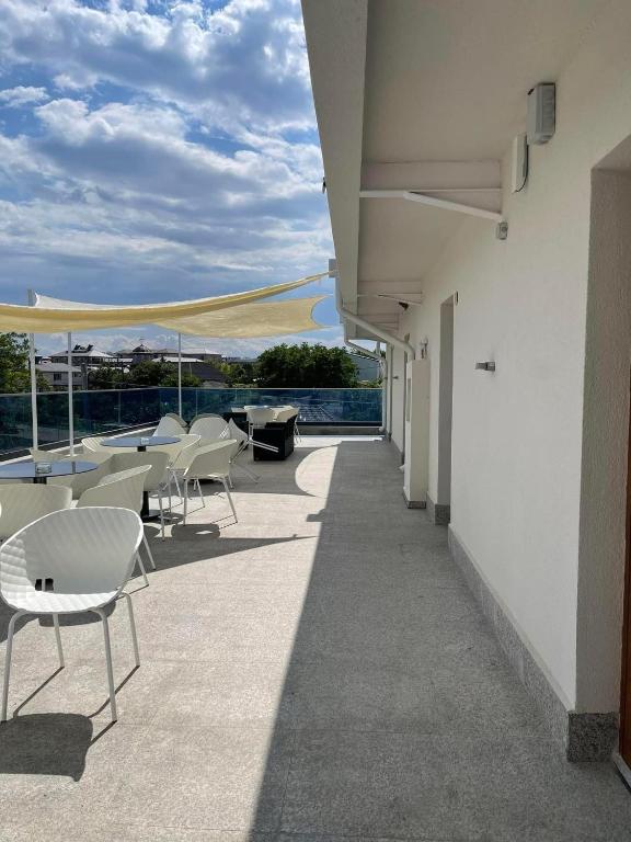 a balcony with white chairs and tables on a building at Polu-X in Vama Veche