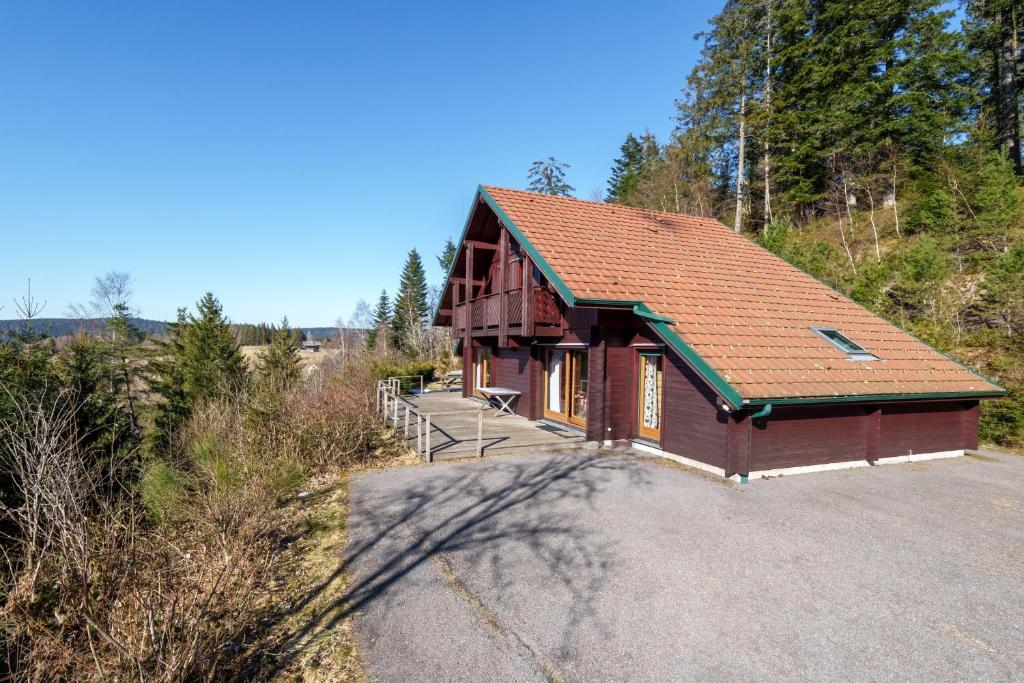 une petite maison avec un toit rouge sur une route dans l'établissement Le Chalet du Xetté - Sauna et vue montagne, à Gérardmer