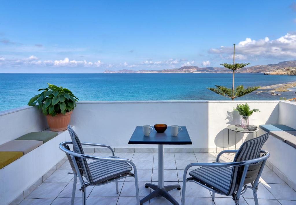 a balcony with a table and chairs and the ocean at Beachfront Blue Comfort Sitia By ComfortBnb in Sitia